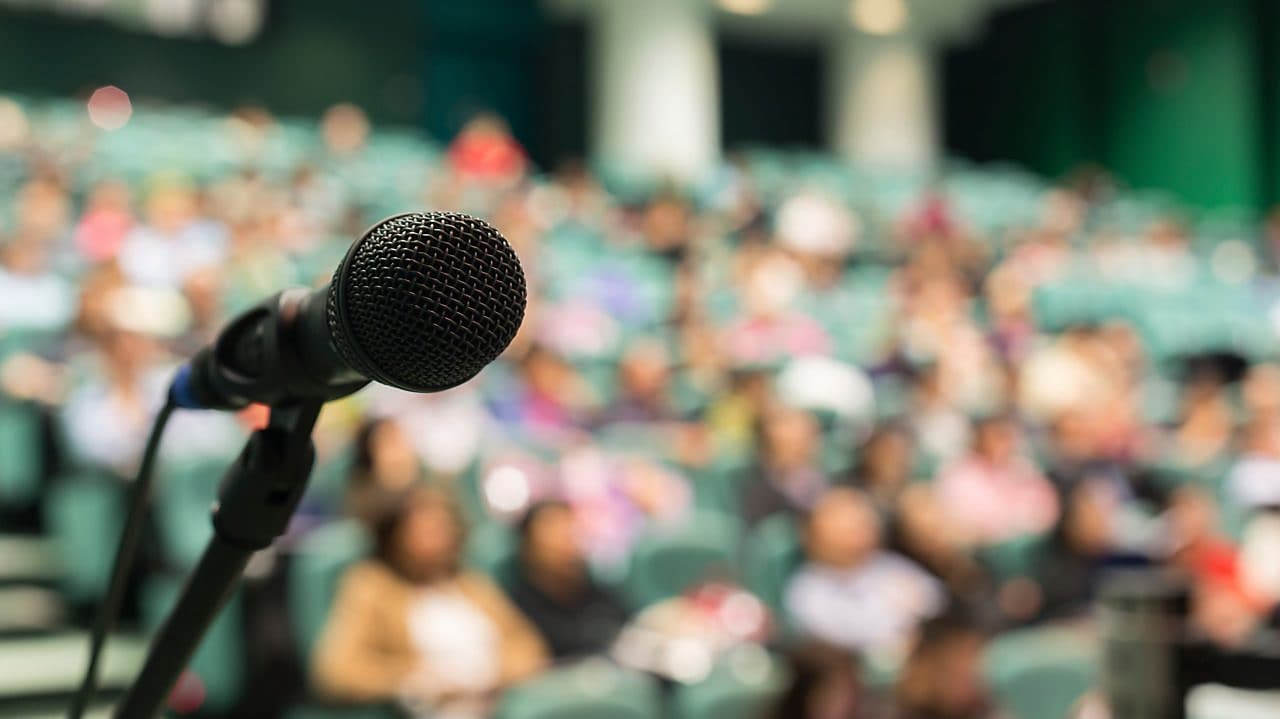 Ortada mikrofon ve arka planda insanlar