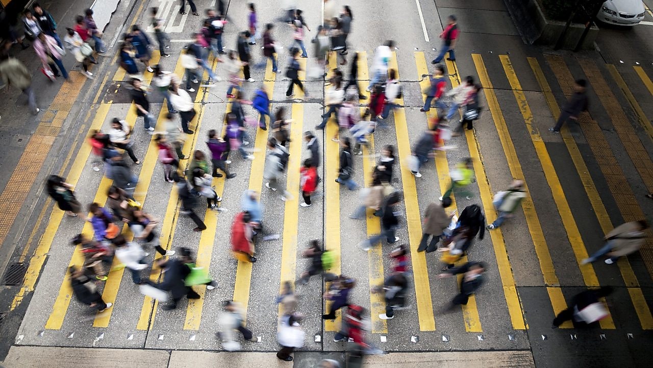 Hong Kong'da işlek bir caddeden karşıya geçen insanlar