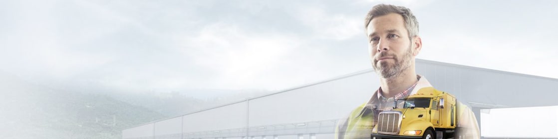 işyerinde sarı bir tırın önünde döküman okuyan adam
