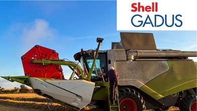 Tarlada büyük bir biçerdöverin basamaklarını çıkan bir çiftçi - Shell Gadus Gresleri