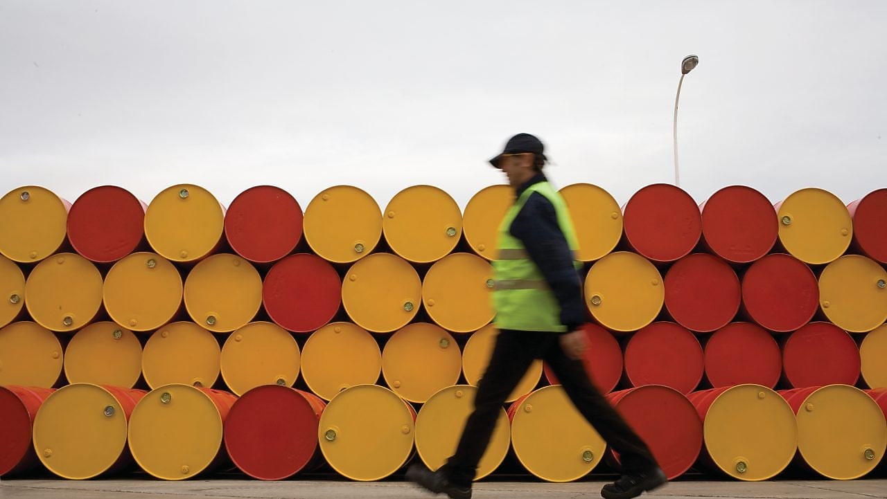 yağlayıcı varillerinin önünde yürüyen adam