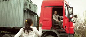 Kapısı açık kırmızı kamyondaki adam kızına el sallıyor