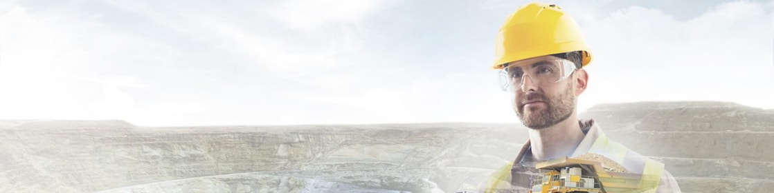 kayalıklar ve sarı büyük bir kamyon fonuna oturtulan sarı baretli işçi