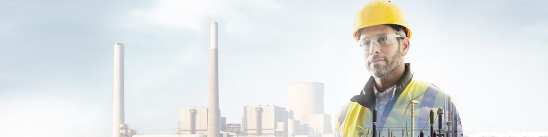 Arka plandaki elektrik santralında sarı baretli işçi