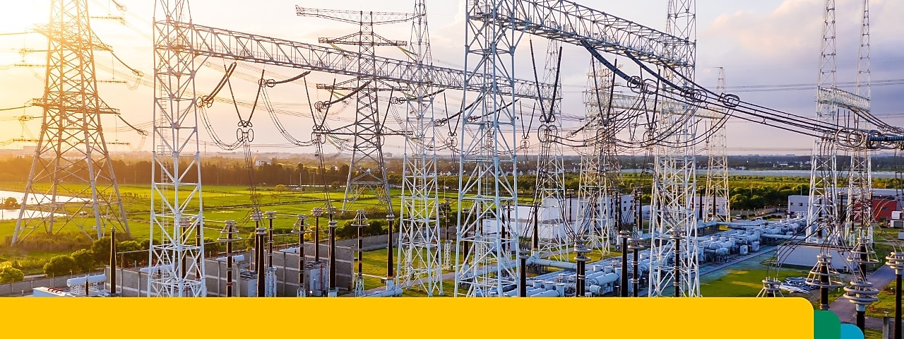 Gün batımında birbirine bağlı yüksek voltajlı iletim hatları ve ekipmanları içeren bir elektrik güç trafo merkezi.