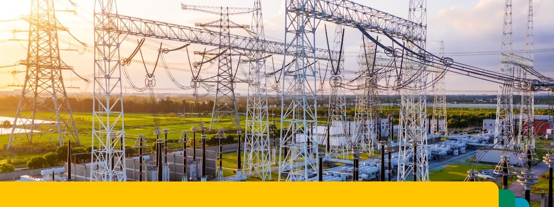 Gün batımında birbirine bağlı yüksek voltajlı iletim hatları ve ekipmanları içeren bir elektrik güç trafo merkezi.