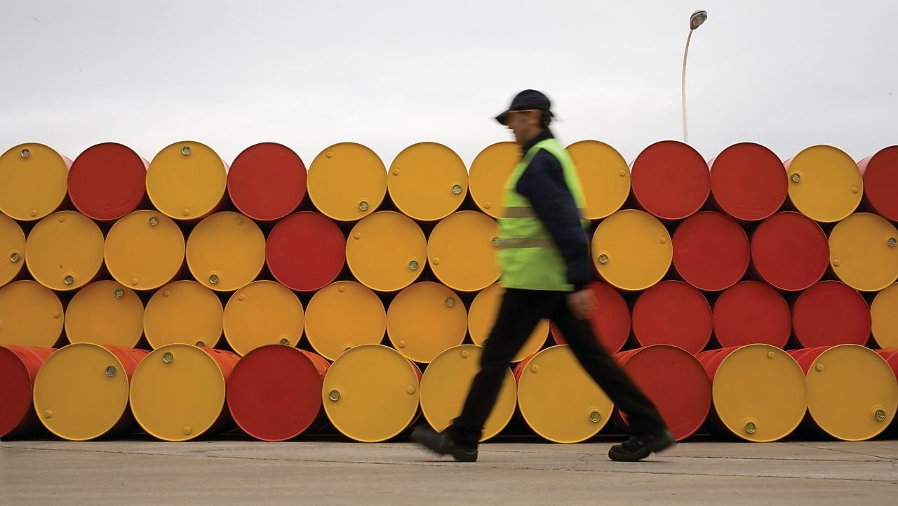 yağlayıcı varillerinin önünde yürüyen adam