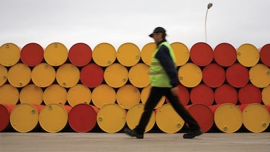 yağlayıcı varillerinin önünde yürüyen adam