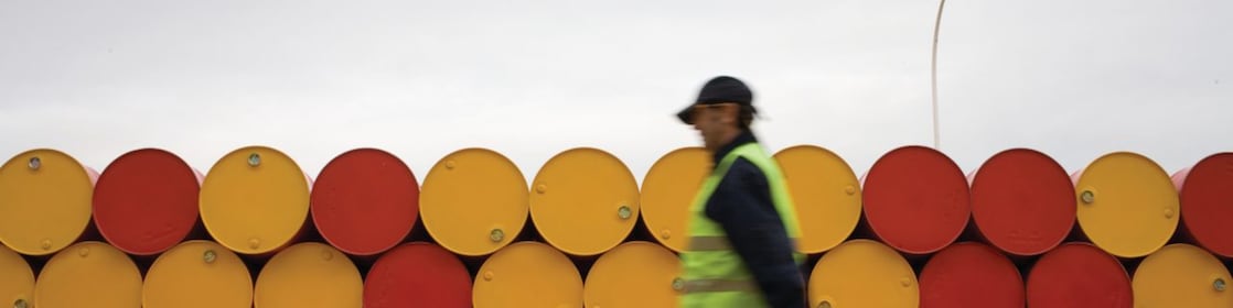 yağlayıcı varillerinin önünde yürüyen adam