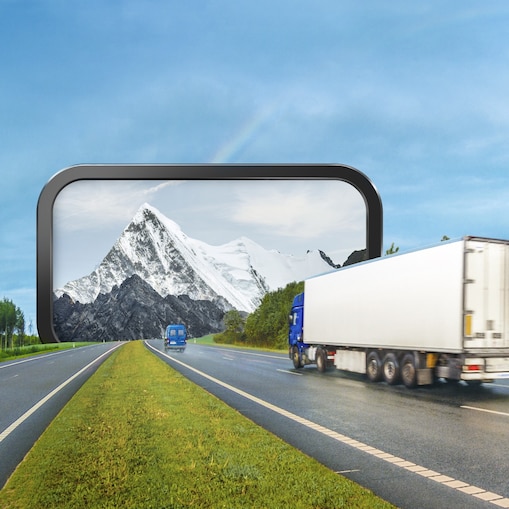 Ein Lkw fährt durch ein fiktives Tor in die Berge.