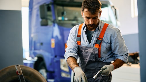 Ağır vasıta servisinde bir kamyon üzerinde çalışırken iş aletleri kullanan teknisyen.