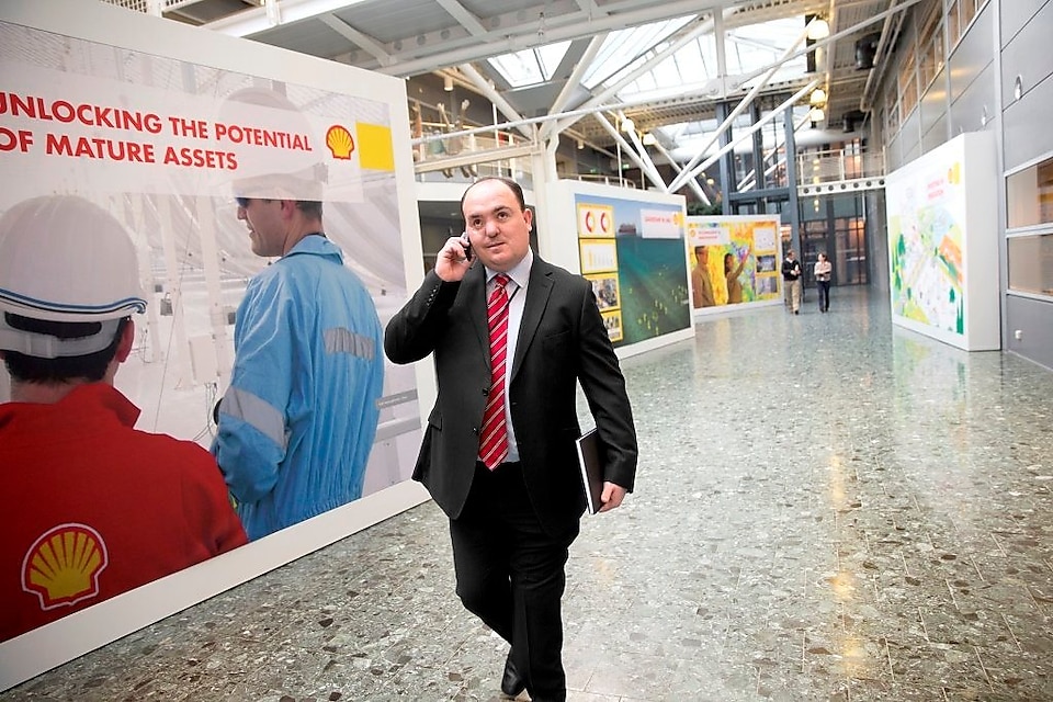 Andy Kneen bir Shell ofisinde yürürken telefonda konuşuyor
