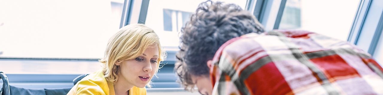 Tekerlekli sandalyeli bir kadın bir erkekle konuşuyor