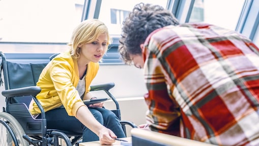 Tekerlekli sandalyeli bir kadın bir erkekle konuşuyor