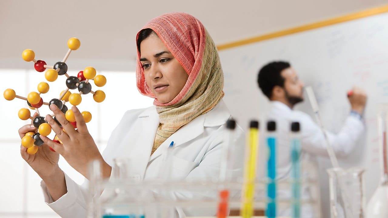 Genç bir bayan bilim insanı moleküler bir modeli inceliyor