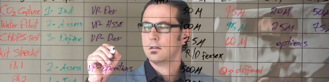 şeffaf yazı tahtasına yazı yazan çalışan.