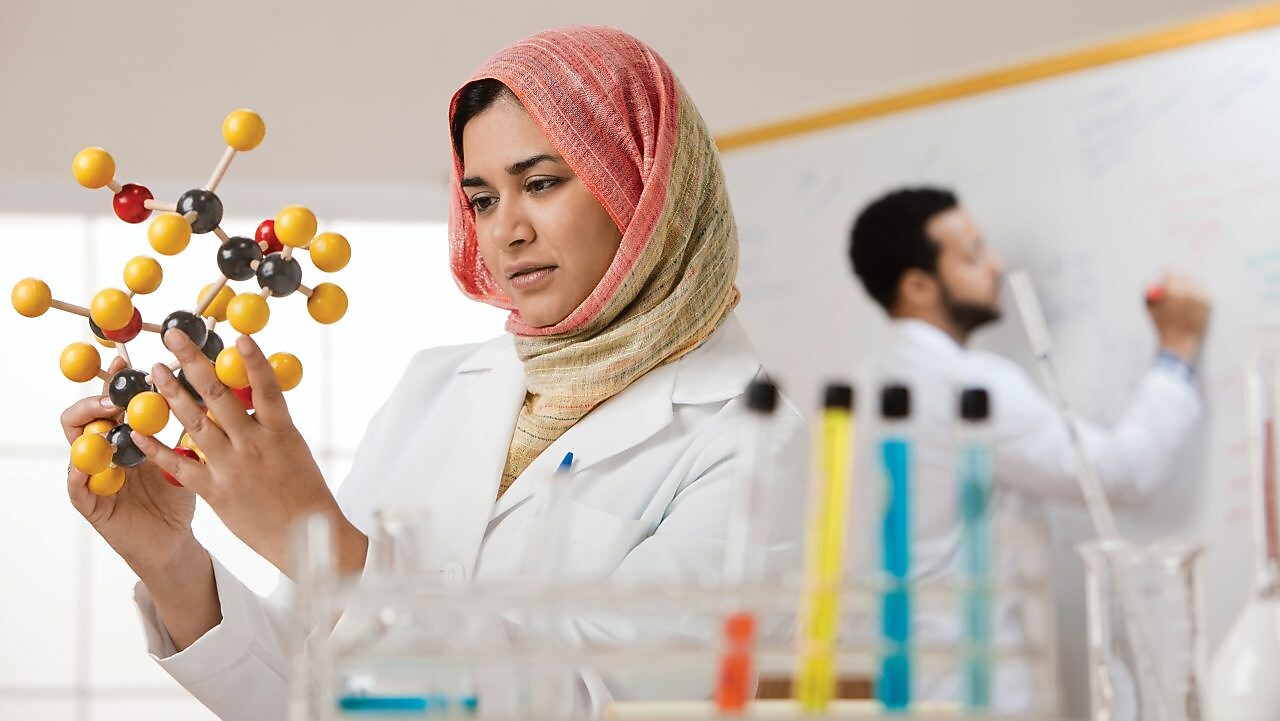 Genç bir bayan bilim insanı moleküler bir modeli inceliyor