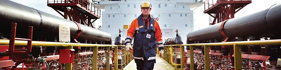 Shell gemisinin etrafında yürüyen işçi