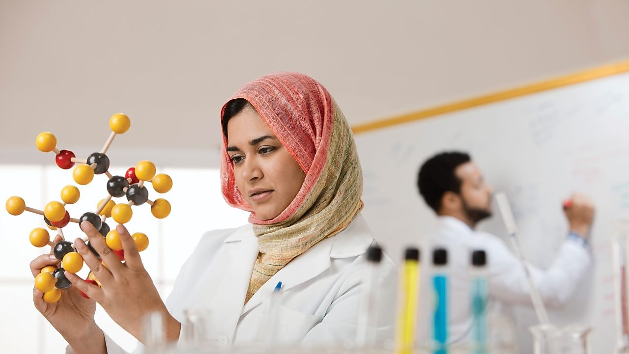 Genç bir bayan bilim insanı moleküler bir modeli inceliyor