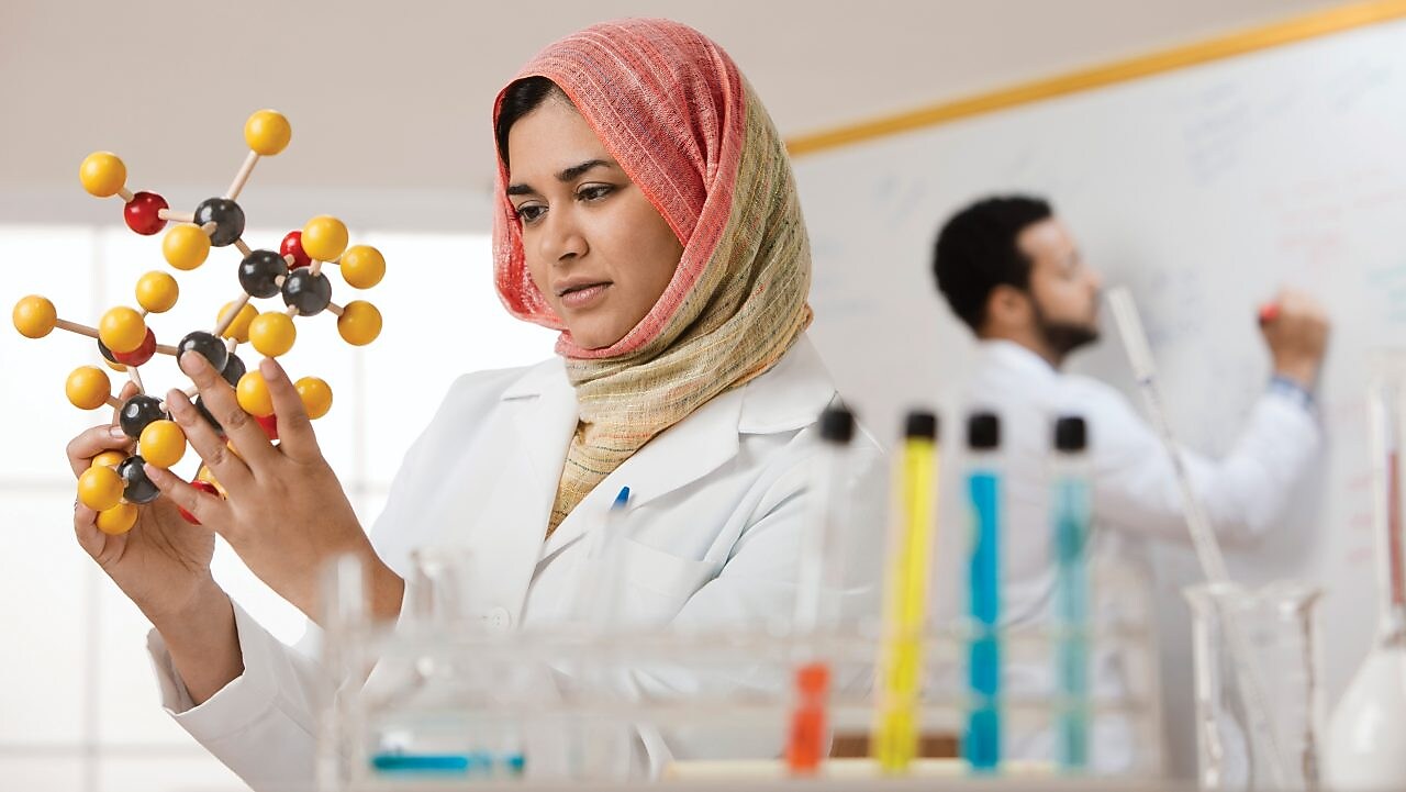 Genç bir bayan bilim insanı moleküler bir modeli inceliyor