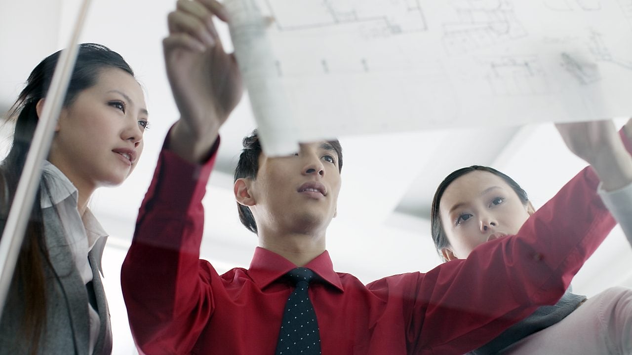 İşteyken tasarım planlarını tartışan mezunlar