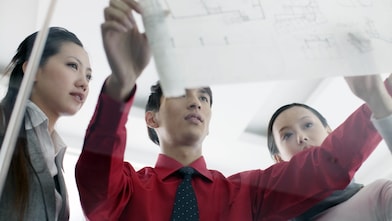 İşteyken tasarım planlarını tartışan mezunlar