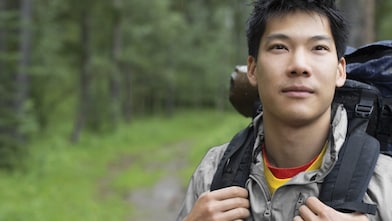 Ağaçlıktaki sırt çantalı bir Asyalı erkeğin portresi