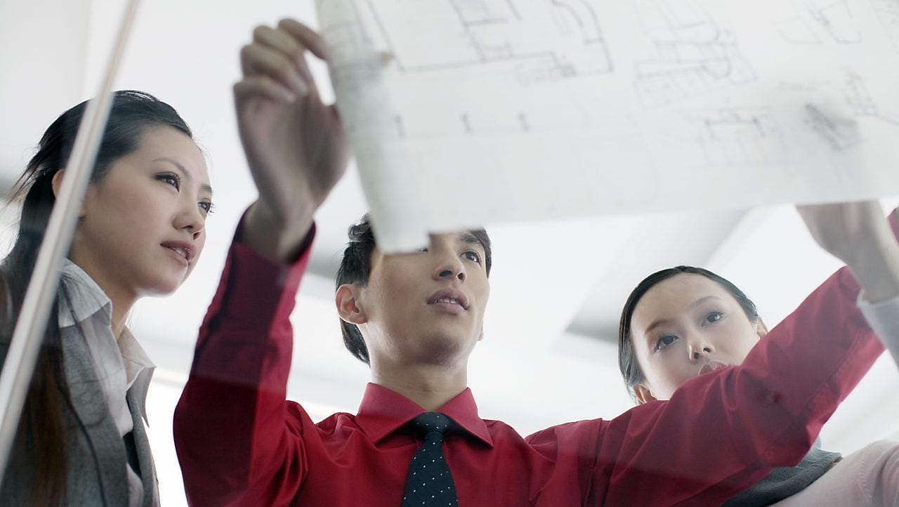 bir adam, çalışma arkadaşlarına taslak gösteriyor