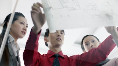 bir adam, çalışma arkadaşlarına taslak gösteriyor