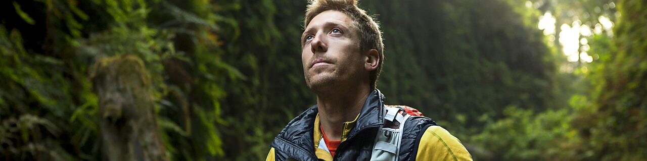 genç bir adam Redwood ormanında bisiklet sürüyor.