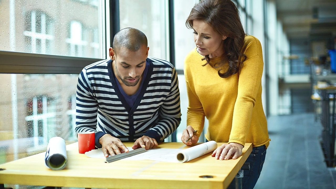 İki mimar yüksek masada bir projeyi tartışıyor
