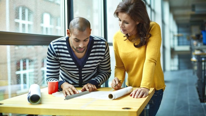 İki mimar yüksek masada bir projeyi tartışıyor