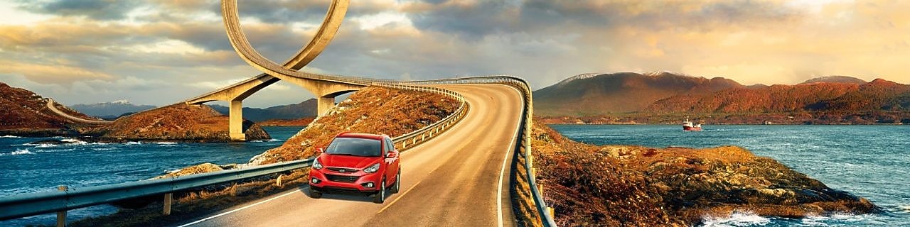 Red car driving on the road by the river