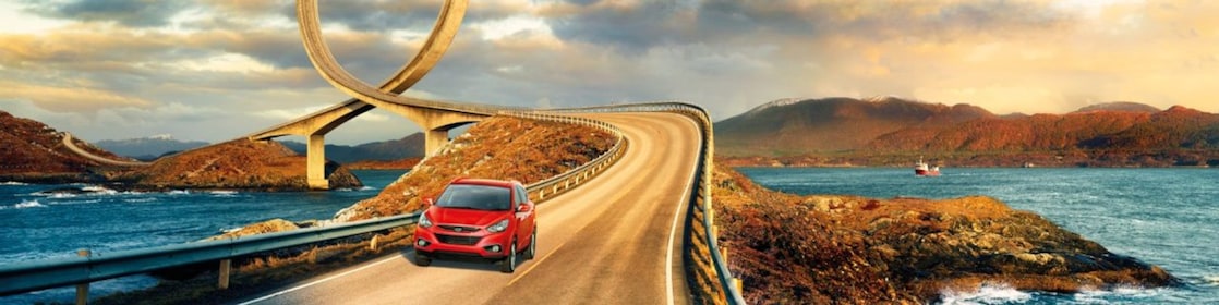 Red car driving on the road by the river