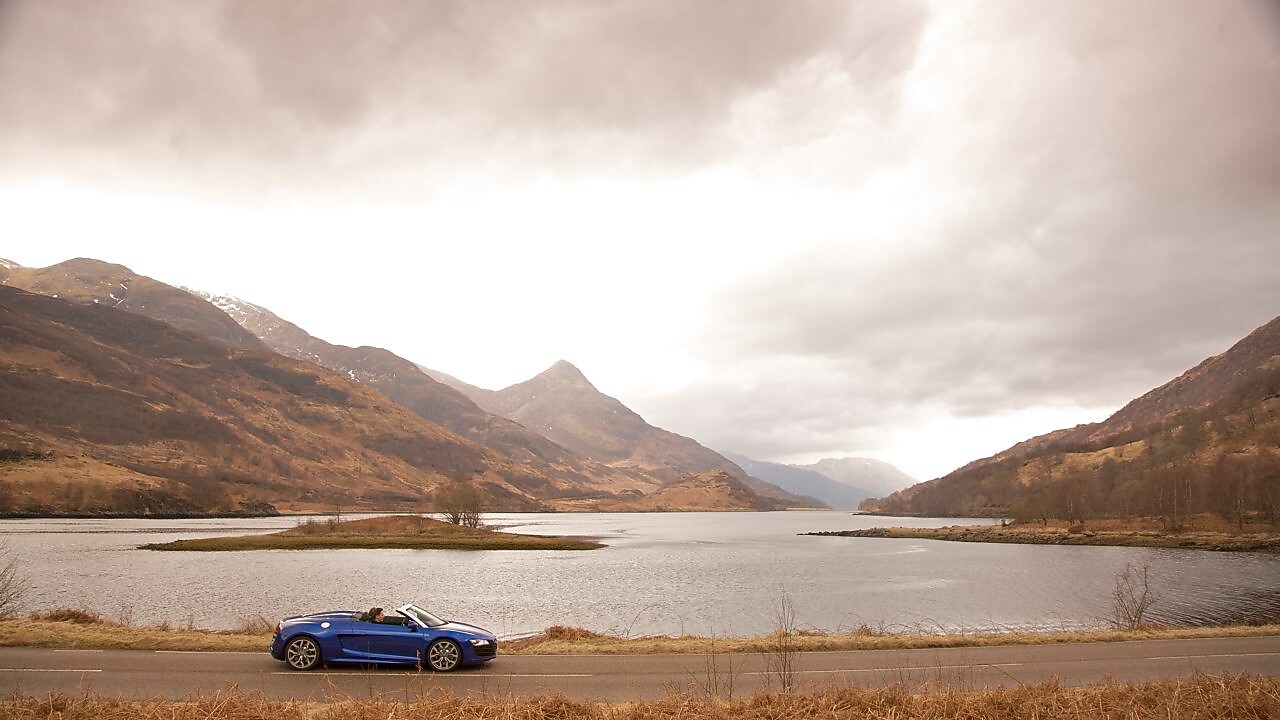 Mavi otomobil gölün yanından geçiyor