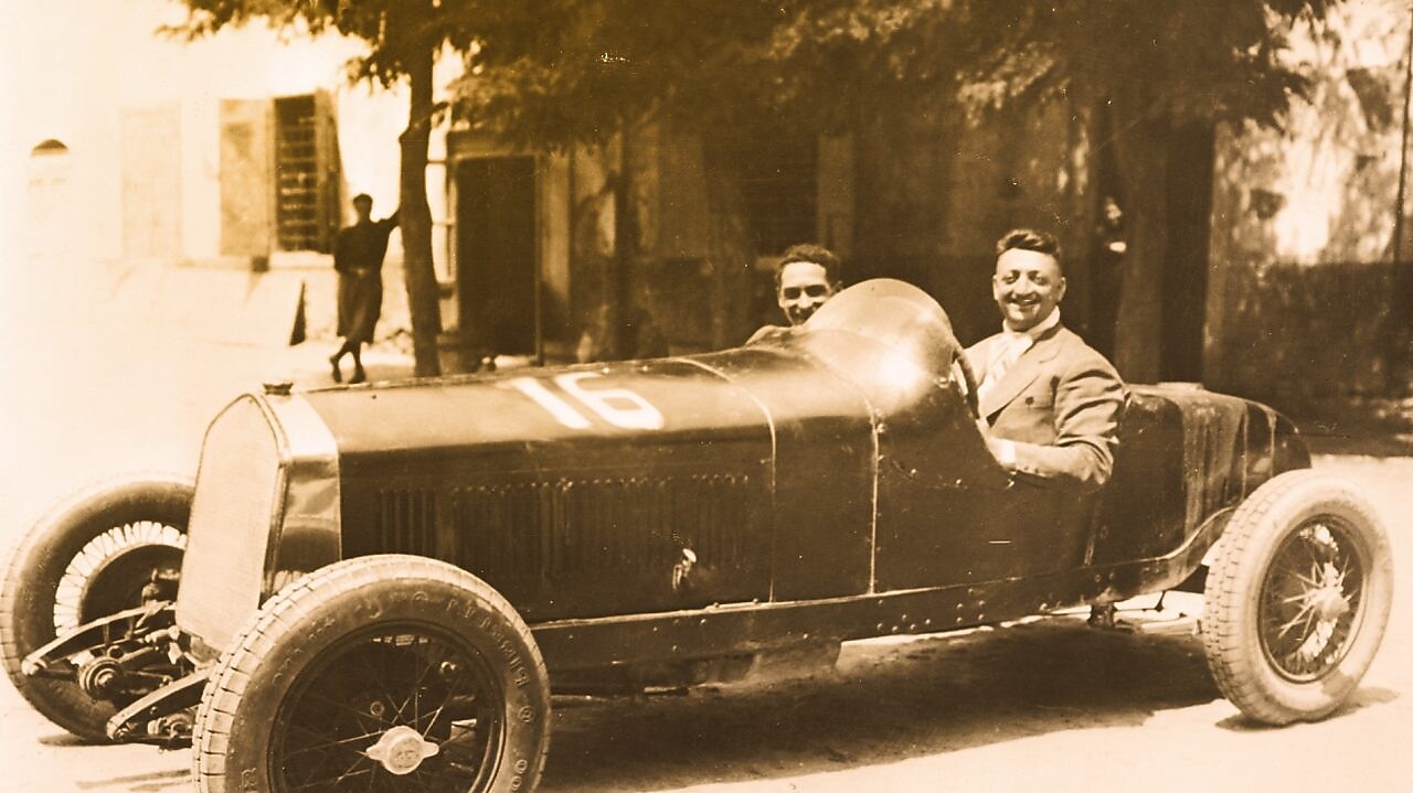 Enzo Ferrari ilk Ferrari otomobillerinden birinde otururken çekilmiş siyah beyaz fotoğraf