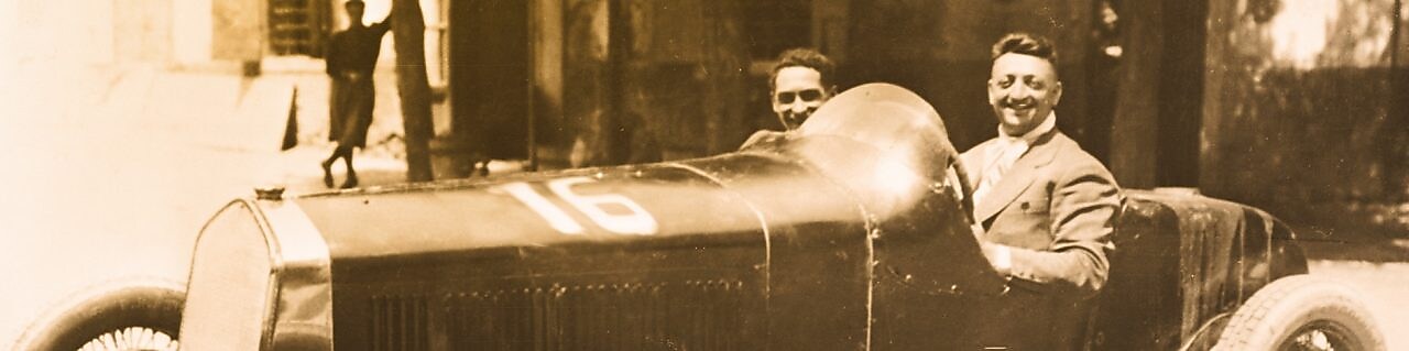 Enzo Ferrari ilk Ferrari otomobillerinden birinde otururken çekilmiş siyah beyaz fotoğraf