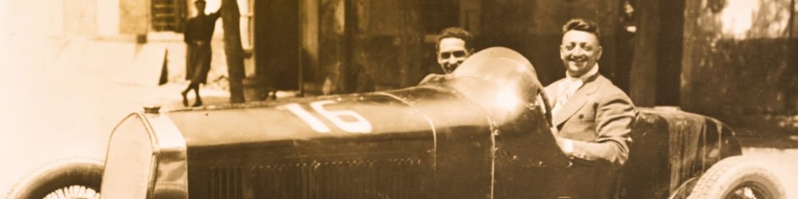 Enzo Ferrari ilk Ferrari otomobillerinden birinde otururken çekilmiş siyah beyaz fotoğraf