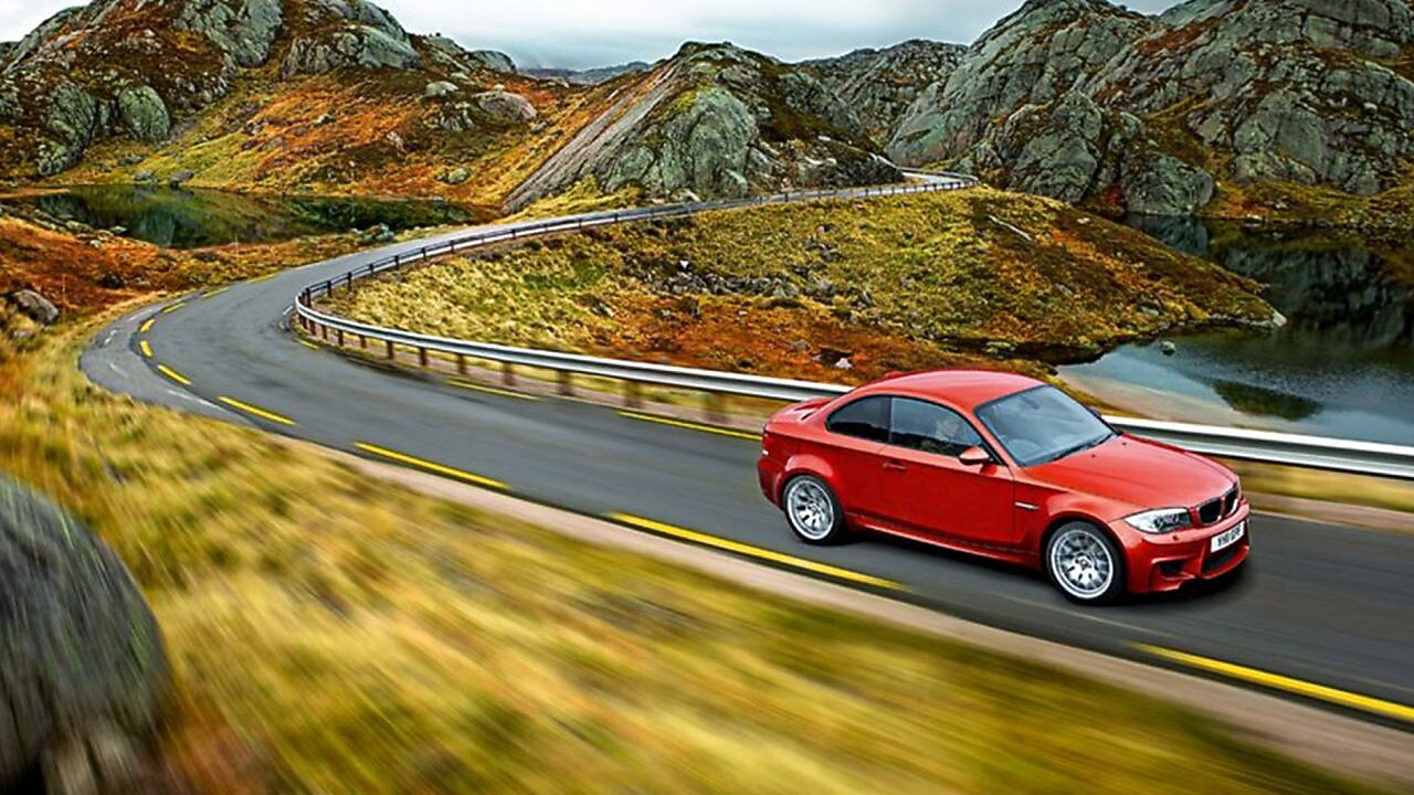 Kırmızı otomobil Norveç’te yolda gidiyor