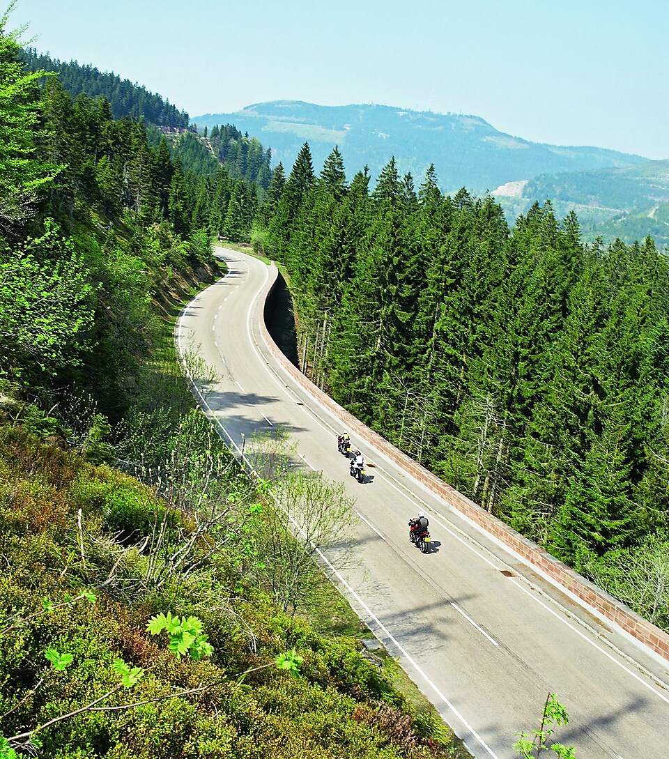 Üç motosiklet üç şeritli bir dağ yolunda yarışıyorlar