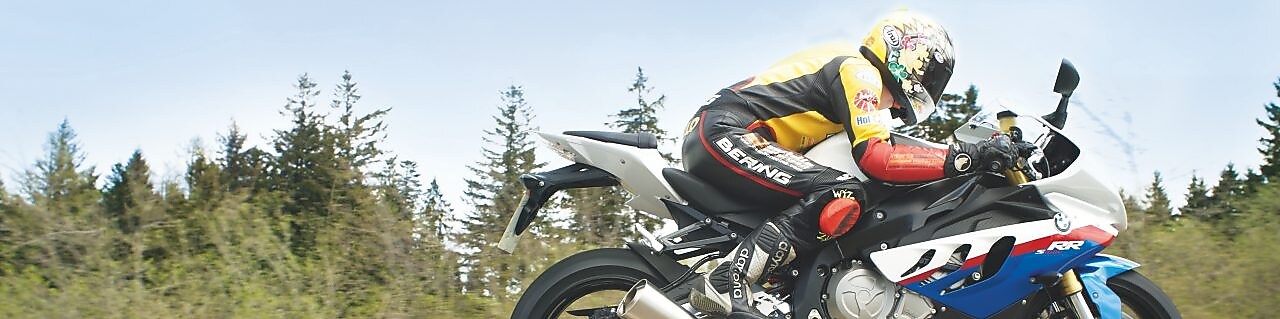 Bir adam taşra yolunda motosiklet kullanıyor