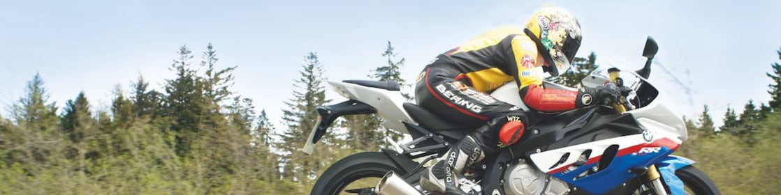 Bir adam taşra yolunda motosiklet kullanıyor