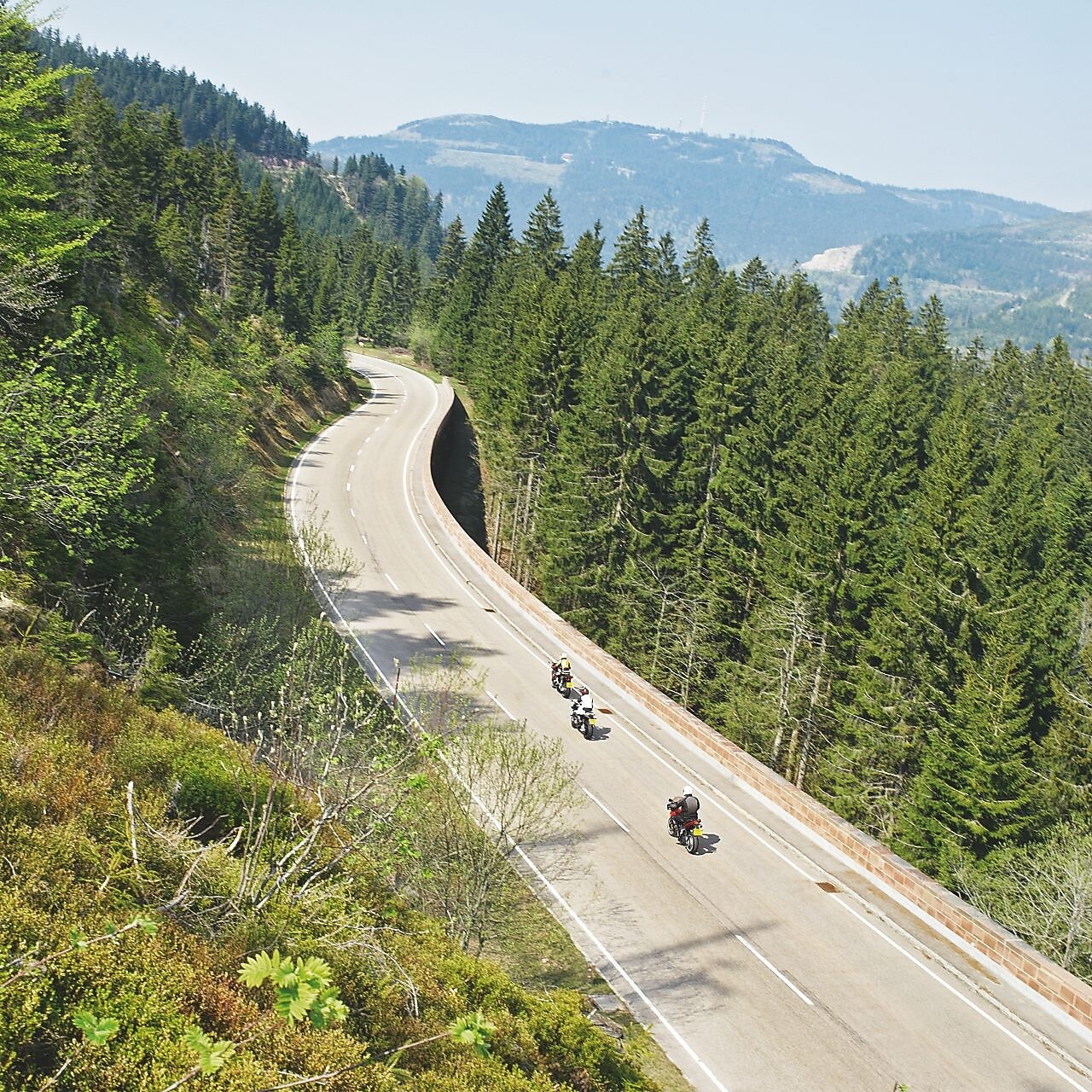 Üç motosiklet üç şeritli bir dağ yolunda yarışıyorlar