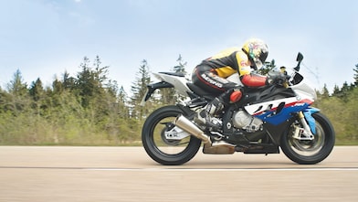 Bir adam taşra yolunda motosiklet kullanıyor