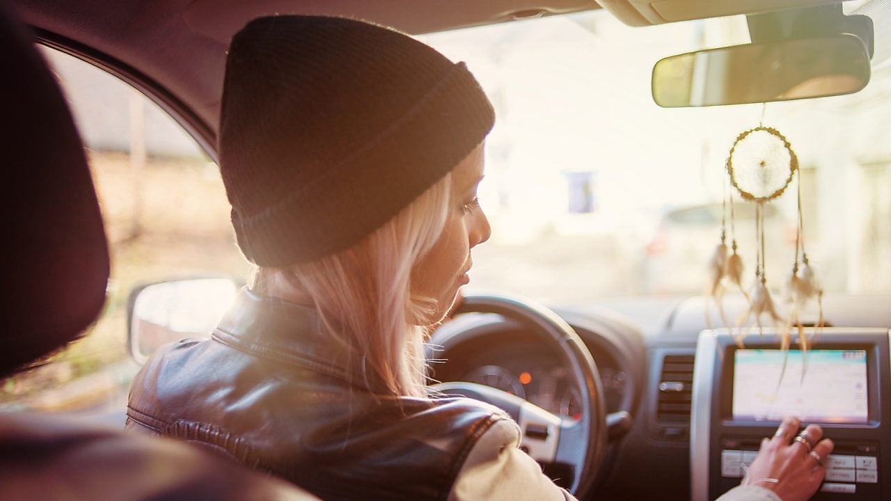 Genç bir kadın otomobilinin navigasyon ekranından yol tarifini kontrol ediyor