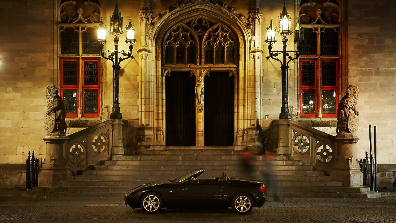 Gece siyah bir araba büyük bir evin önüne, taş basamakların yanına park edilmiş