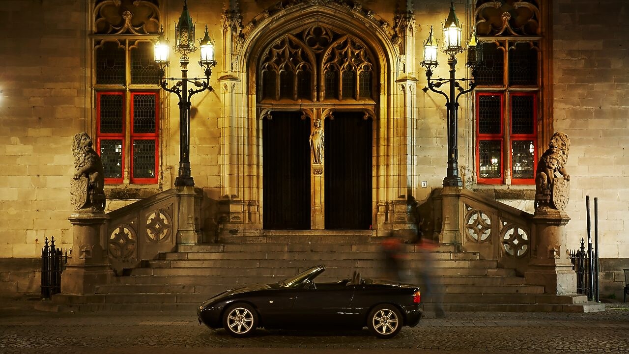 Gece siyah bir araba büyük bir evin önüne, taş basamakların yanına park edilmiş