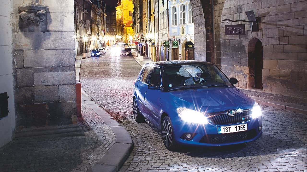 Gece, bir kemerin altında, arnavut kaldırımlı yolda park etmiş mavi otomobil