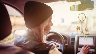 Genç bir kadın otomobilinin navigasyon ekranından yol tarifini kontrol ediyor