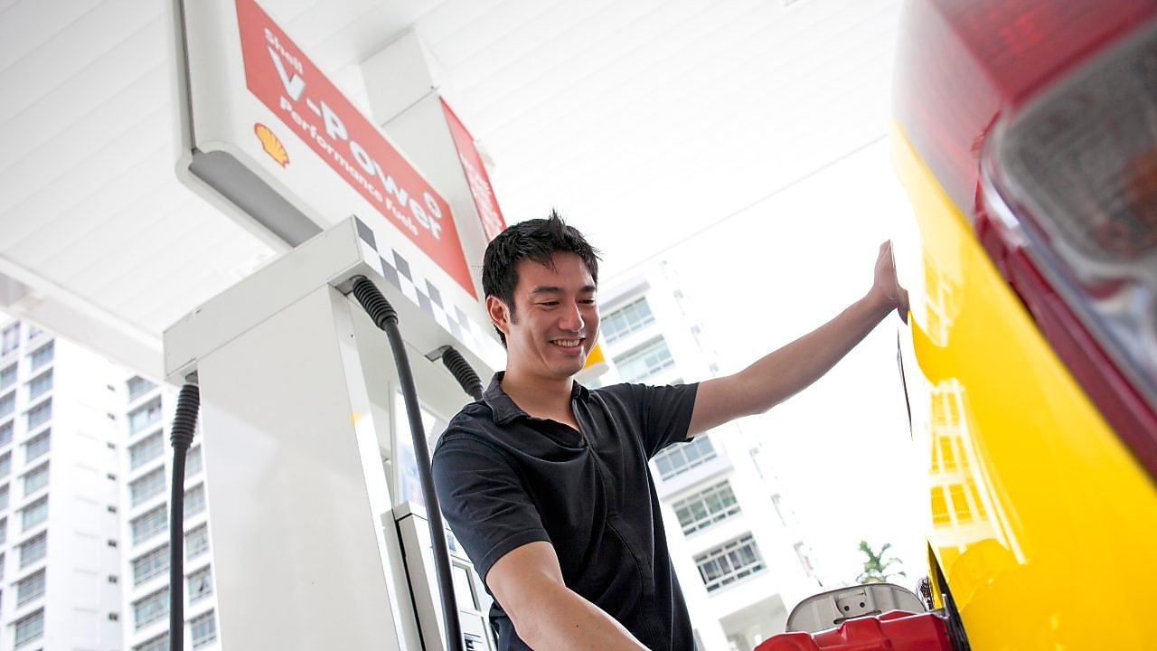 Bir adam benzin pompasında arabasının deposunu dolduruyor